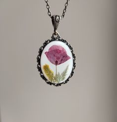 The real pressed poppy flower necklace was made with handpicked and dried poppy and epoxy resin. The poppy is encased in bronze oval frame with clear resin. The resin protects the flower and at the same time it magnifies their beauty.  The sizes of the pendant is 3.7 cm x 4.6 cm. The chain length is 64 cm and it's closed with a lobster clasp.  This vintage necklace can be: - A perfect poppy gift for flower lovers, - a birthday gift, an anniversary gift or a christmas gift for women; for your gir Poppy Colored Flower Shaped Jewelry Gift, Poppy Colored Flower Shaped Gift Jewelry, Poppy Flower-shaped Jewelry Gift, Poppy Flower Shaped Jewelry Gift, Flower-shaped Soldered Necklaces For Gifts, Flower Shaped Soldered Necklaces For Gifts, Flower Shaped Necklaces With Soldered Details For Gifts, Dried Poppy, Poppy Necklace