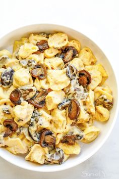 a white bowl filled with pasta covered in mushroom and cheese sauce on top of a table