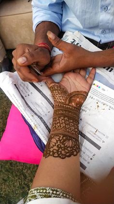 two people are holding their hands together with hendi tattoos on each hand and writing on the paper