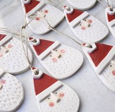 christmas ornaments with santa hats and bells are on the table, ready to be hung