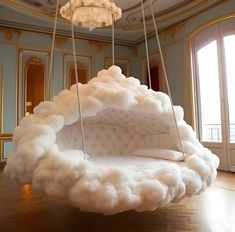 a bed made out of foam is suspended by chains in a room with chandelier