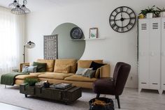 a living room filled with furniture next to a large window and clock on the wall