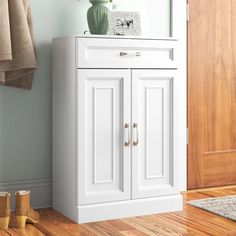 a white cabinet sitting on top of a hard wood floor next to a wooden door