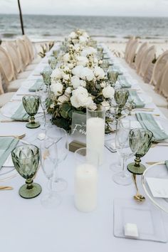 a long table with white flowers and candles on it