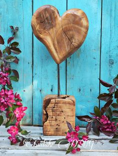 a wooden heart on top of a box next to flowers