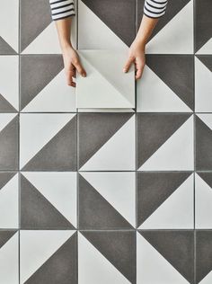 a person standing on top of a white and gray tile floor next to a wall