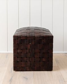 a brown leather ottoman sitting on top of a hard wood floor next to a white wall