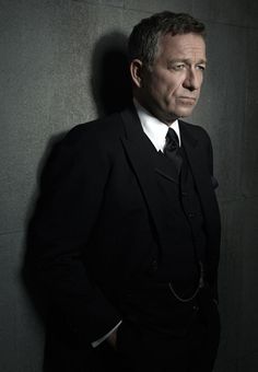 a man in a suit and tie standing against a wall