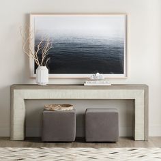 two stools sit under a painting on the wall next to a table with a vase