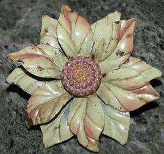 a flower brooch sitting on top of a stone table next to a black surface