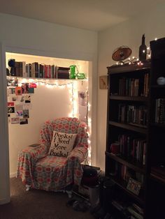 a living room with a chair and bookshelf filled with lots of bookcases