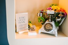 an old fashioned phone sitting on top of a shelf next to flowers and a note