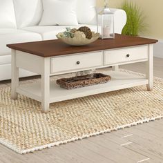 a living room with a white couch, coffee table and rug on the floor in front of it