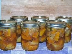 several jars filled with pickles sitting on top of a blue and white checkered table cloth