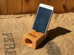 a cell phone is in a wooden holder on a burlap surface with the word'woodgrain'printed on it