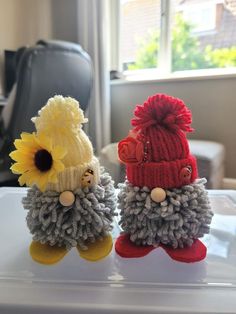 two small knitted sheep with hats and flowers on their heads, sitting next to each other