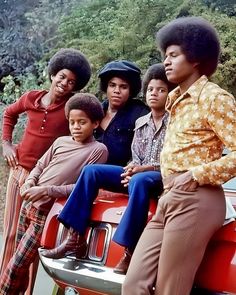 a group of people sitting on top of a red car