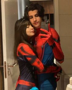 a man and woman in spiderman costumes taking a selfie