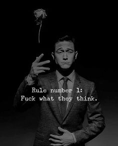 a man in a suit holding a rose up to his face with the caption, rules number 1 fock what they think