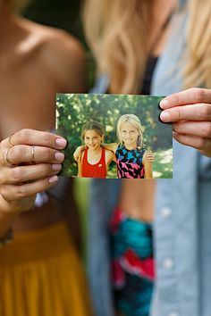 two women holding up an old photo in their hands