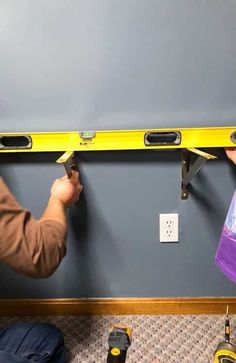 two men are working on a wall with tools and tape measure the width between them