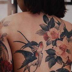 the back of a woman's body with flowers and birds on it