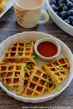 some waffles are on a white plate with blueberries and syrup in the background