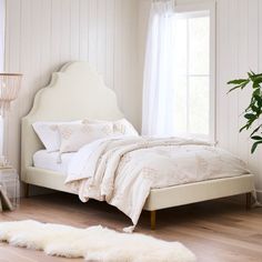 a white bed sitting next to a window in a room with wooden floors and walls