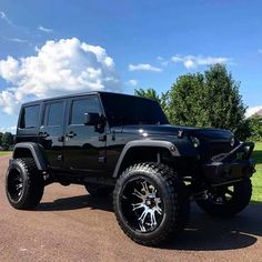 a black jeep parked on the side of a road next to a field and trees