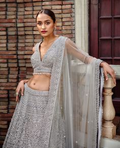 Editor's Note Silver Grey Tulle Lehenga Set Adorned With Silver Zari Dabka , Dori, Sequins Beads And Crystals. Color: Grey Fabric: Tulle Components: Lehenga, Blouse & Dupatta Care: Dry Clean Only About the Designer Nitika Gujral’s journey with designing clothes started almost four decades back while she was still in high school and held her first exhibition for family and friends. Making clothes has been a part of her life ever since. Tulle Lehenga, Sequin Lehenga, Designing Clothes, Blouse Yoke, Personal Shopping Service, Making Clothes, Lehenga Blouse, How To Make Clothes, Sequin Beading