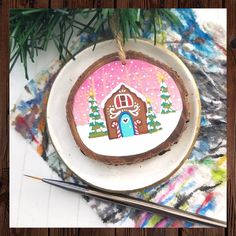 a christmas ornament on a plate next to some scissors and paintbrushes