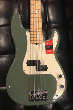 a green bass guitar sitting on top of a black leather couch