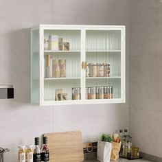 a kitchen with white cabinets and silver counter tops in front of a wall mounted oven