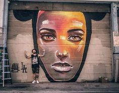 a man standing in front of a garage door with a mural on it's side