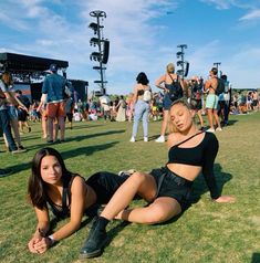 two women are laying on the grass at a music festival