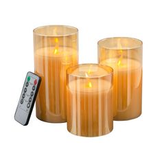 three candles and a remote control on a white background