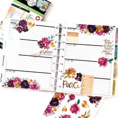 an open planner with flowers on it and the words grace written in gold foil is next to a notepad