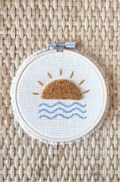 a cross stitch sun and the ocean on a white background with some blue water in it