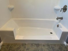 a white bath tub sitting on top of a tiled floor