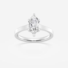 a white gold ring with an oval cut diamond in the center, set on a plain surface