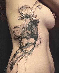 a woman's stomach with a bird and flowers tattoo on the side of her body