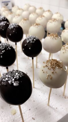 chocolate cake pops with gold sprinkles are on a white tablecloth lined up