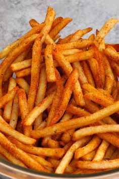 a glass bowl filled with french fries sitting on top of a cement floor covered in seasoning