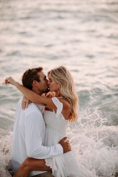 a man and woman are kissing in the water at the beach while they both have their arms around each other