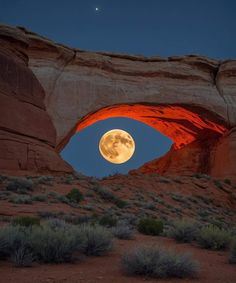 the full moon is seen through an arch in the desert