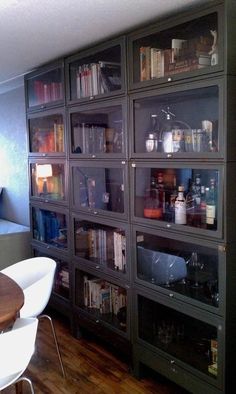 a room filled with lots of glass shelves next to a wooden table and white chairs