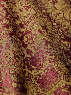 a red and gold fabric with an intricate design on it's surface, close up