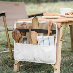 an outdoor picnic table with utensils and wooden spoons in the back pocket