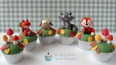 a group of cupcakes that have animals on top of them and mushrooms in the middle