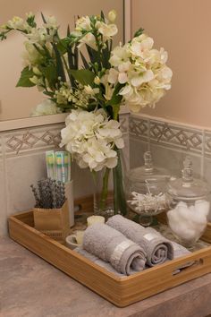 a wooden tray with towels and flowers in it